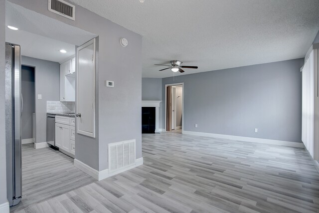 empty room featuring a textured ceiling, light hardwood / wood-style floors, and ceiling fan