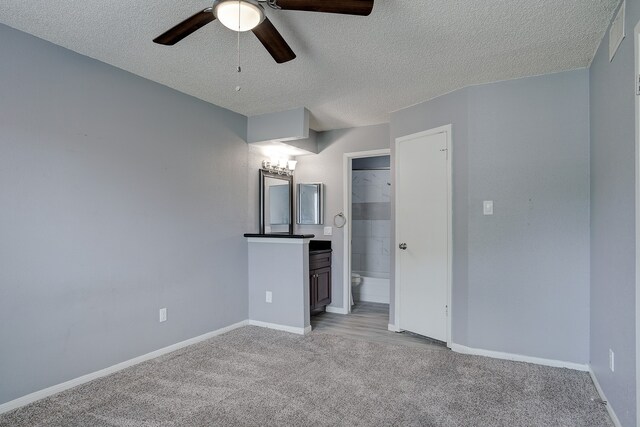 unfurnished bedroom featuring ceiling fan, a textured ceiling, a closet, and light carpet