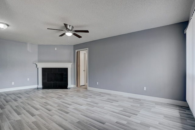 unfurnished living room with a textured ceiling, a fireplace, ceiling fan, and light hardwood / wood-style flooring