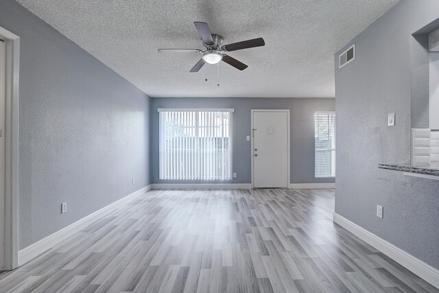 unfurnished living room with a textured ceiling, light hardwood / wood-style floors, and ceiling fan