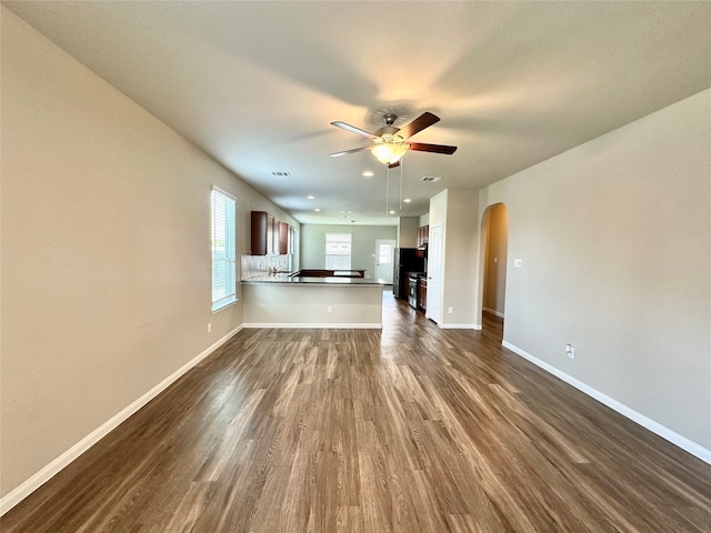 unfurnished living room with ceiling fan and dark wood-type flooring