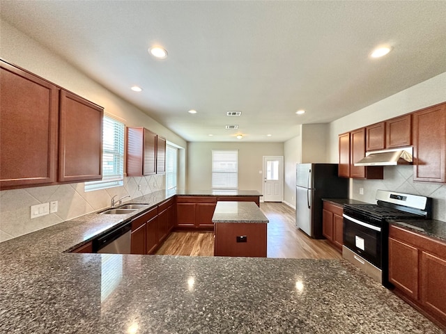 kitchen with stainless steel appliances, sink, decorative backsplash, and light hardwood / wood-style flooring