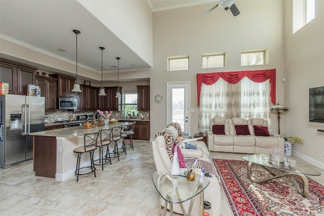 living room with ceiling fan, ornamental molding, and a high ceiling