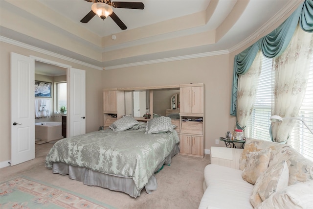 carpeted bedroom with crown molding, connected bathroom, a tray ceiling, and ceiling fan