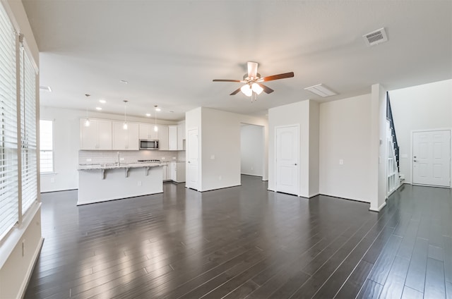 unfurnished living room with dark wood-type flooring and ceiling fan