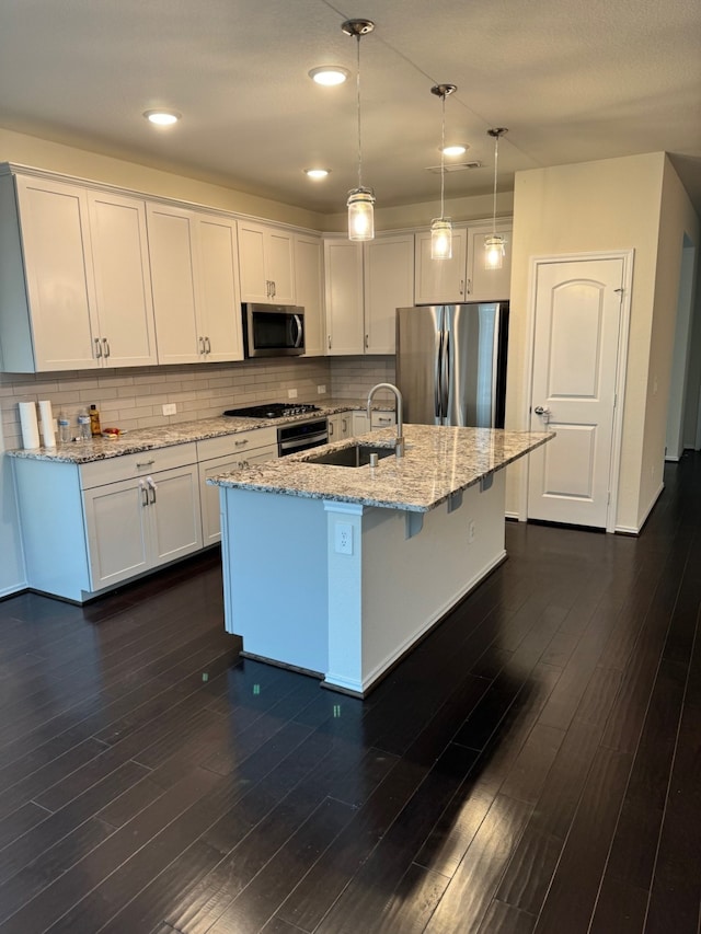 kitchen with appliances with stainless steel finishes, hanging light fixtures, and white cabinetry