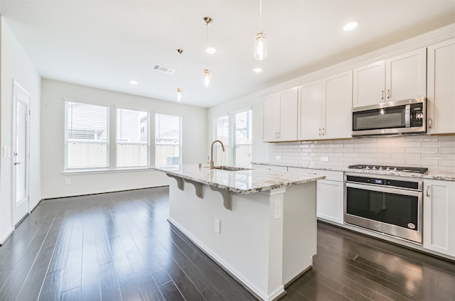 kitchen featuring a kitchen island with sink, white cabinetry, pendant lighting, and stainless steel appliances