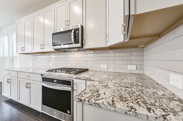 kitchen featuring decorative backsplash, light stone countertops, stainless steel appliances, and white cabinets