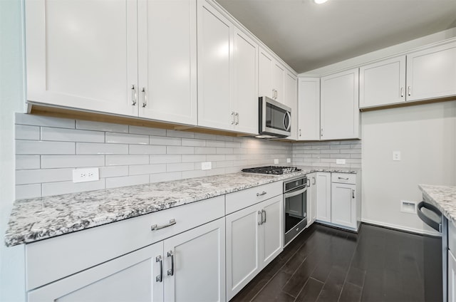 kitchen with dark hardwood / wood-style floors, white cabinetry, backsplash, appliances with stainless steel finishes, and light stone countertops