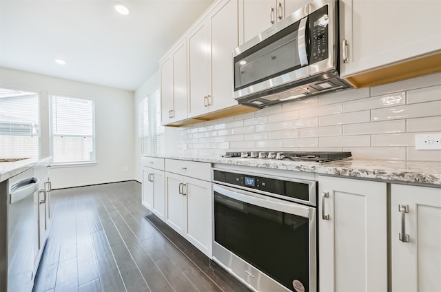 kitchen with light stone counters, tasteful backsplash, white cabinetry, appliances with stainless steel finishes, and dark hardwood / wood-style floors