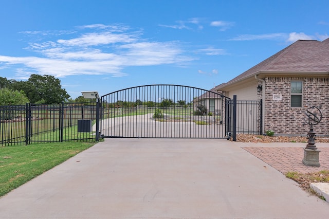 view of gate with a garage and a yard