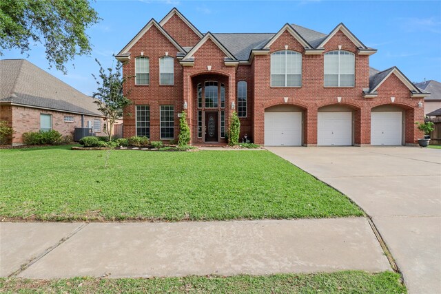 view of property with a front lawn, central AC unit, and a garage