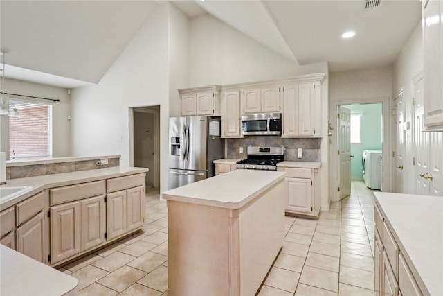 kitchen featuring stainless steel appliances, light tile patterned flooring, a kitchen island, and washing machine and dryer