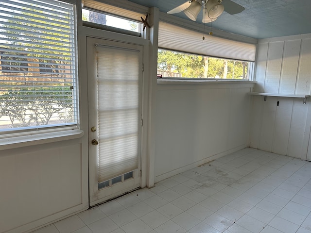 doorway featuring light tile patterned floors, ceiling fan, and a wealth of natural light