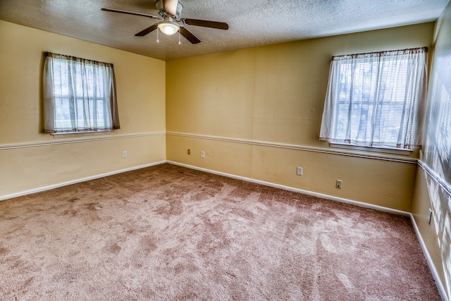 carpeted empty room with ceiling fan, a textured ceiling, and a healthy amount of sunlight