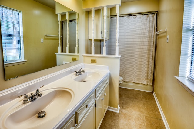 bathroom with a wealth of natural light, tile patterned floors, vanity, and toilet