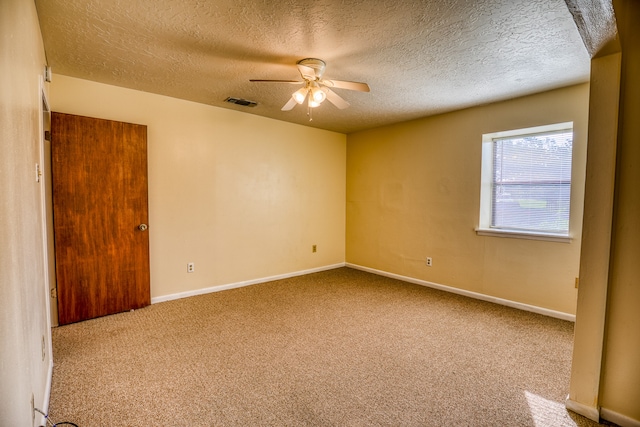 carpeted spare room with ceiling fan and a textured ceiling