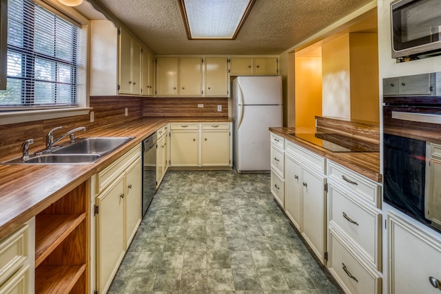 kitchen with a textured ceiling, black appliances, cream cabinets, and sink