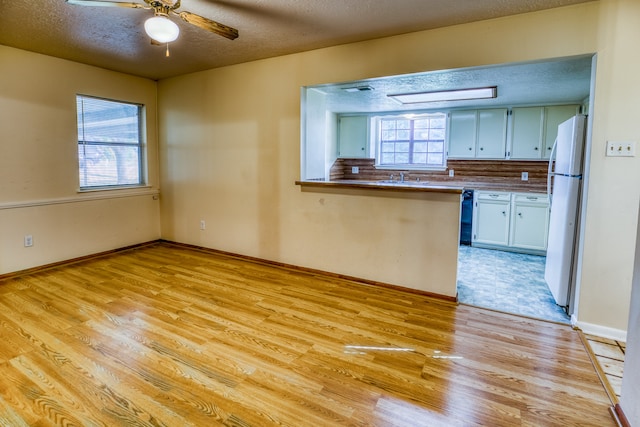 kitchen featuring a healthy amount of sunlight, ceiling fan, light hardwood / wood-style flooring, and white refrigerator