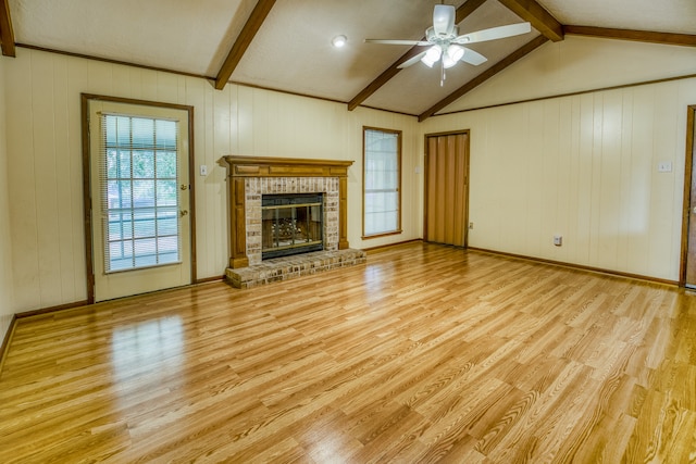 unfurnished living room featuring ceiling fan, light hardwood / wood-style flooring, a fireplace, and lofted ceiling with beams