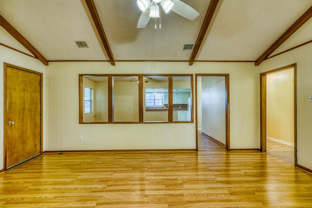 empty room with vaulted ceiling with beams, light hardwood / wood-style floors, ceiling fan, and a textured ceiling