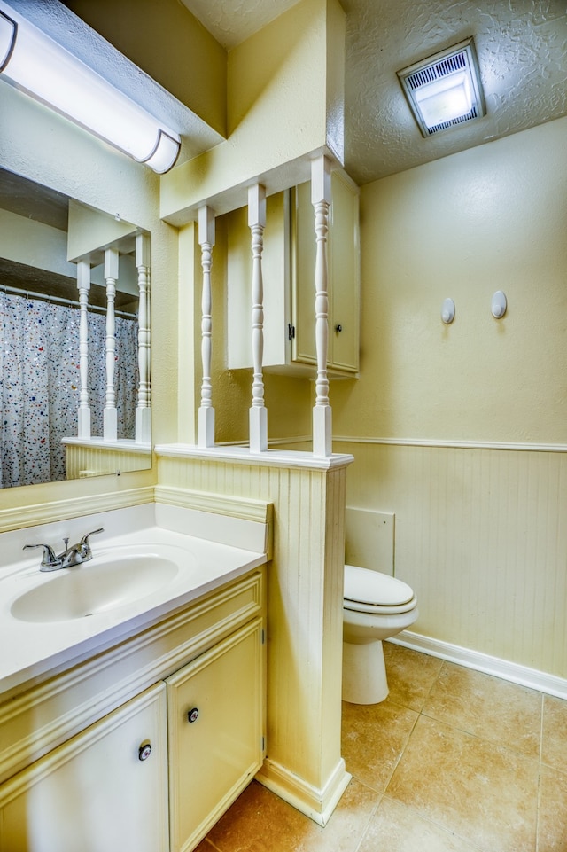 bathroom with a textured ceiling, tile patterned flooring, vanity, and toilet