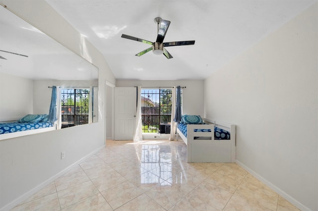 empty room featuring ceiling fan, light tile patterned flooring, vaulted ceiling, and a healthy amount of sunlight