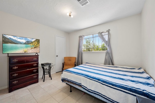 bedroom with a textured ceiling and light tile patterned floors