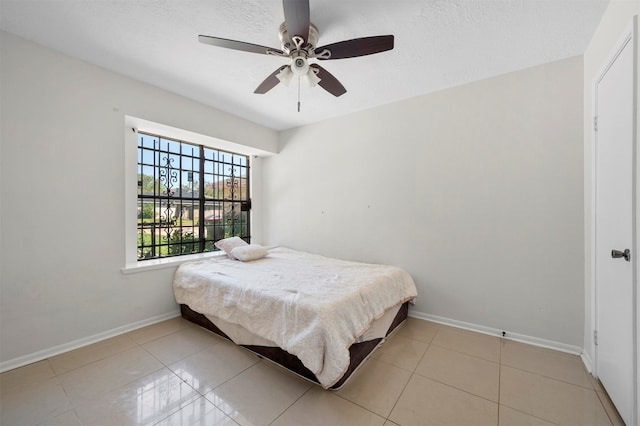 tiled bedroom featuring ceiling fan and a textured ceiling