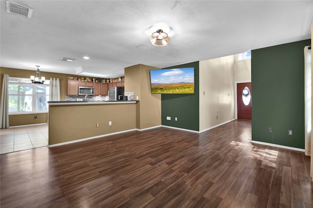 unfurnished living room featuring a textured ceiling, hardwood / wood-style floors, and a notable chandelier