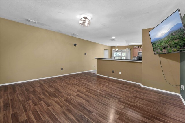 empty room featuring a textured ceiling and dark hardwood / wood-style flooring