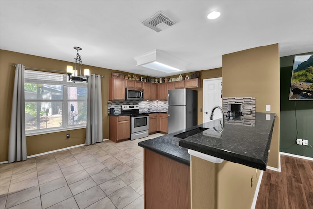 kitchen with pendant lighting, kitchen peninsula, tasteful backsplash, stainless steel appliances, and an inviting chandelier