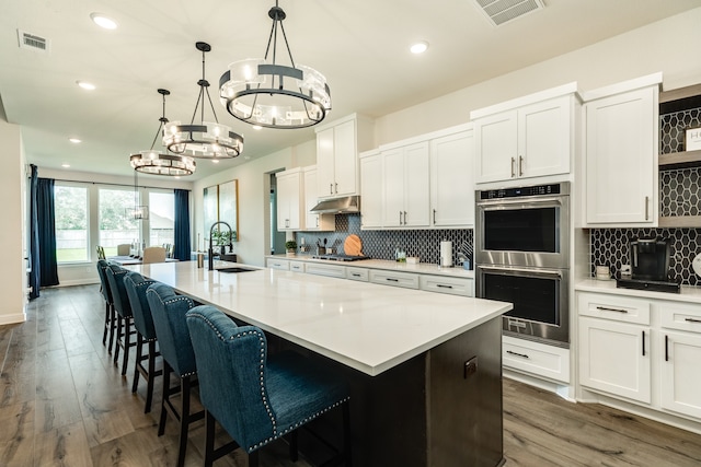 kitchen featuring stainless steel appliances, white cabinets, and a kitchen island with sink