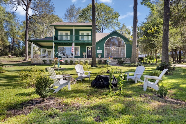 back of property featuring a balcony and a lawn