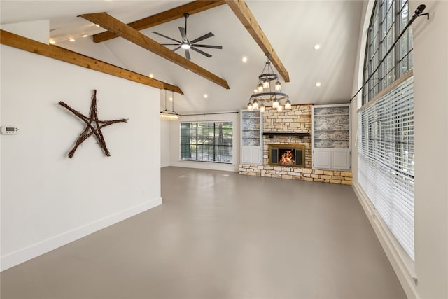 unfurnished living room featuring ceiling fan with notable chandelier, beam ceiling, high vaulted ceiling, a stone fireplace, and concrete floors