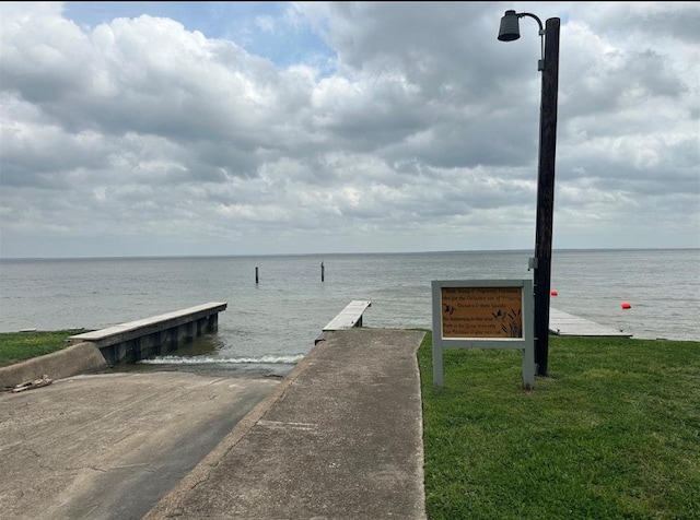 dock area with a water view and a yard