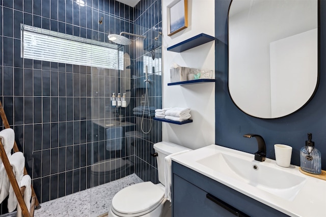 bathroom with a tile shower, vanity, and toilet