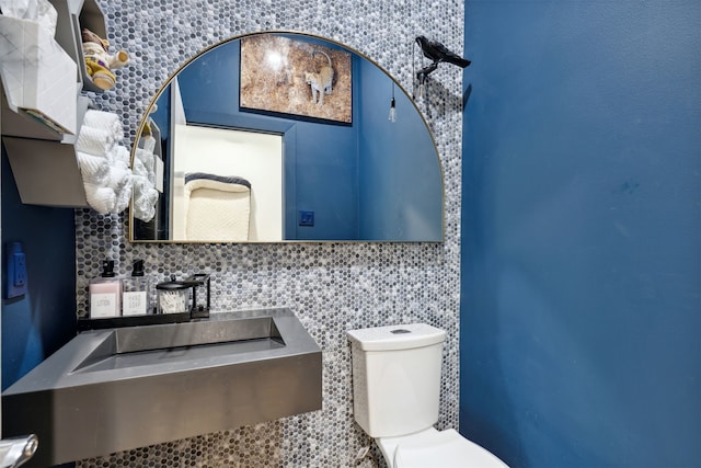 bathroom with tasteful backsplash, toilet, and sink