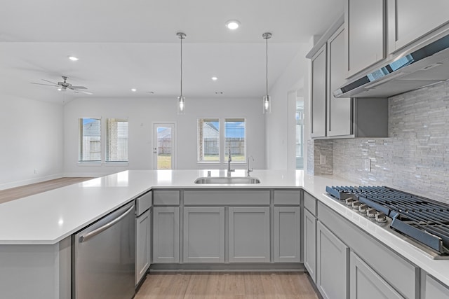 kitchen with kitchen peninsula, stainless steel appliances, sink, and light wood-type flooring