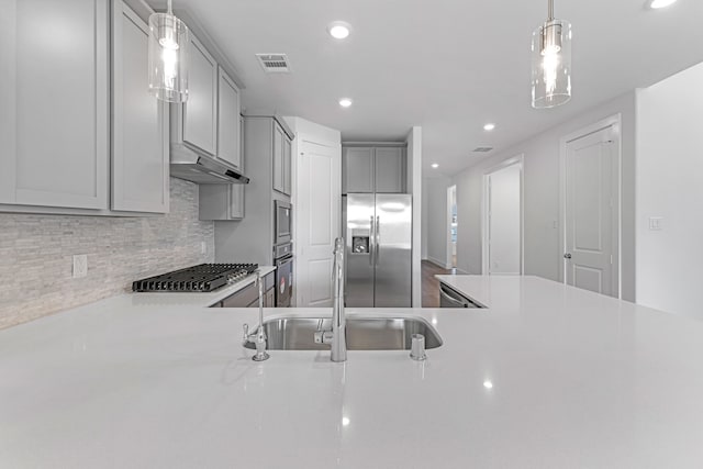 kitchen featuring sink, tasteful backsplash, gray cabinets, appliances with stainless steel finishes, and decorative light fixtures