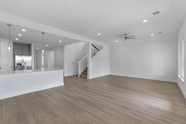 unfurnished living room featuring ceiling fan, sink, and light hardwood / wood-style floors