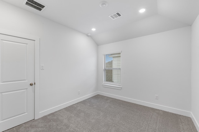 carpeted empty room featuring vaulted ceiling