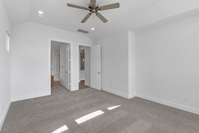 unfurnished bedroom featuring light colored carpet, ceiling fan, vaulted ceiling, and connected bathroom