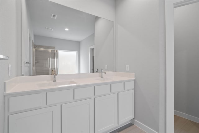 bathroom with hardwood / wood-style flooring, a shower with door, and vanity