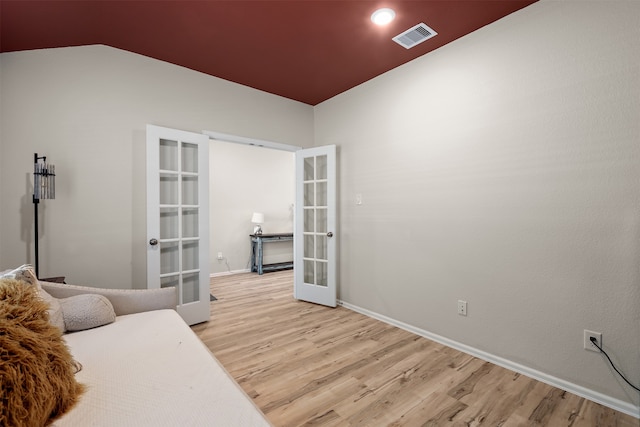 bedroom with french doors, lofted ceiling, and light hardwood / wood-style flooring