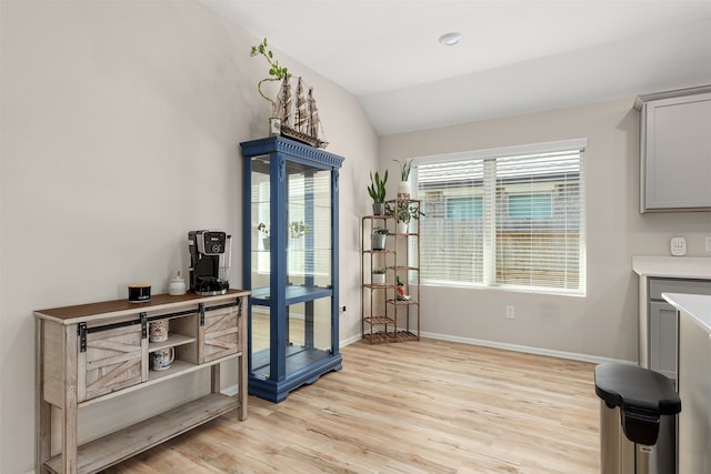 dining space with light wood-type flooring and vaulted ceiling