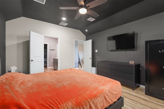 bedroom featuring light hardwood / wood-style floors, vaulted ceiling, ensuite bath, and ceiling fan