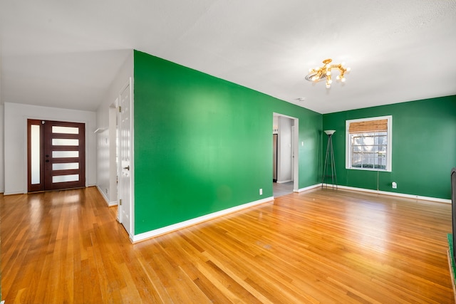 empty room featuring wood-type flooring and a notable chandelier