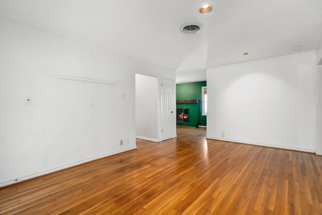 empty room featuring hardwood / wood-style floors and a brick fireplace