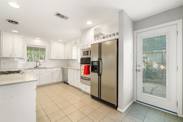 kitchen featuring tasteful backsplash, stainless steel appliances, sink, white cabinetry, and light tile patterned flooring